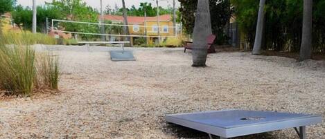Un espacio exterior con mesa de ping pong, red de voleibol y un banco.