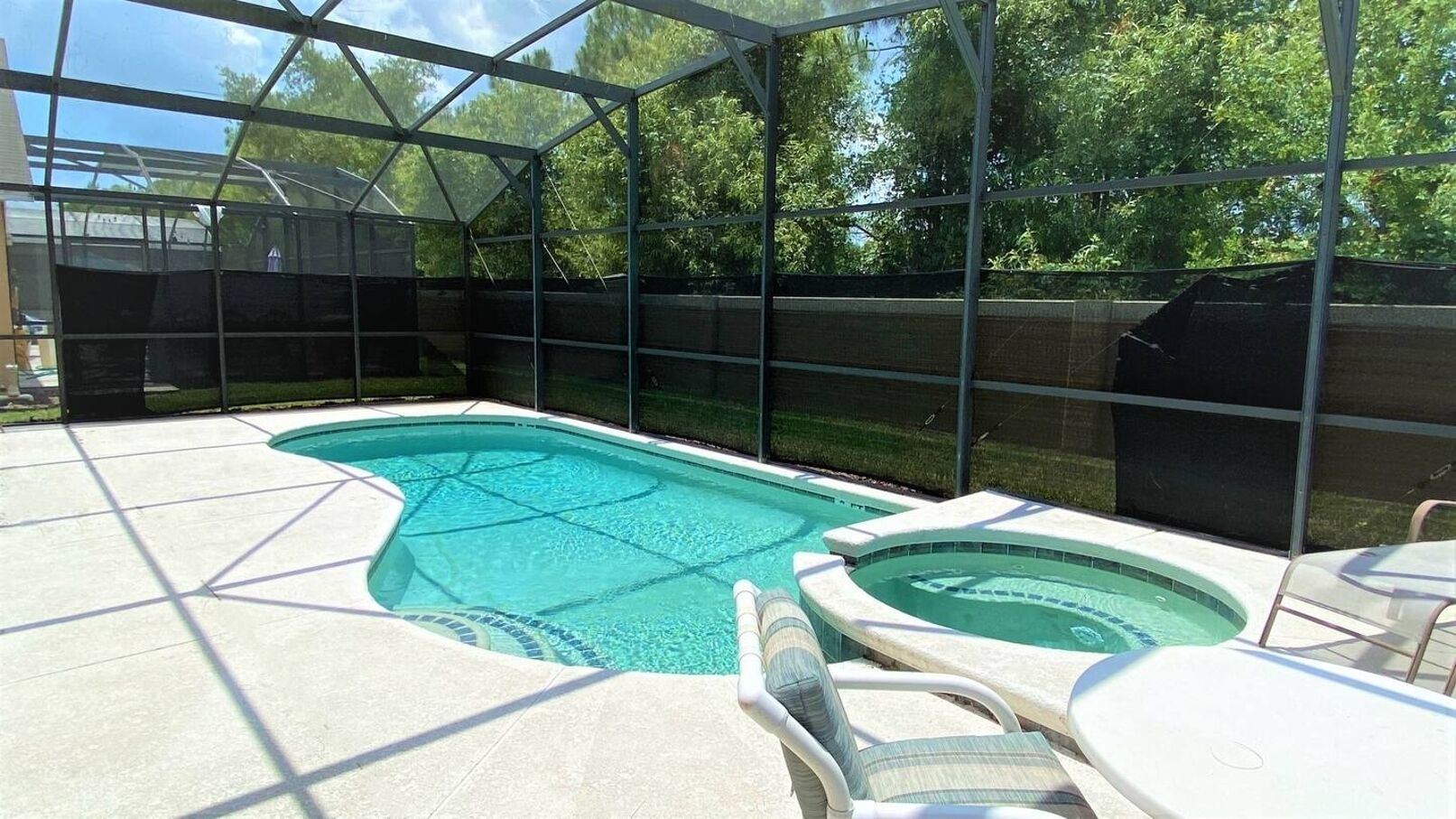 Un patio trasero con piscina, jacuzzi y un área de patio techada.