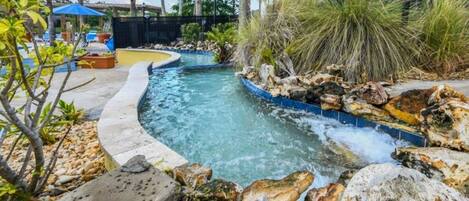 A swimming pool with a curved design, surrounded by rocks and plants.