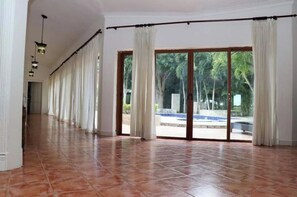 Relax in a serene space with a sliding glass door leading to an outdoor area featuring a pool and palm trees.