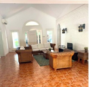 Relax in this inviting living area with a comfortable sofa set, wicker armchairs, and a coffee table.