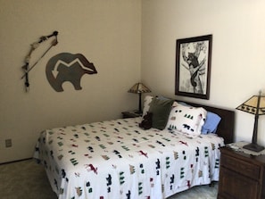 Une chambre à coucher comprenant un lit, deux tables de chevet, une lampe sur chacune, un tableau accroché au mur et un élément décoratif mural.