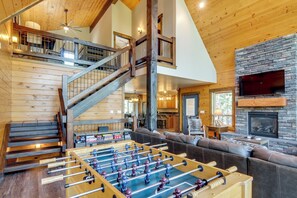 A spacious living area with a foosball table, a fireplace, a large TV, and a staircase leading to an upper level. - 'Longview Lodge' w/ Furnished Deck & Fire Pit! (Alton)