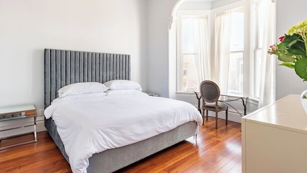 Een moderne slaapkamer met een groot bed, een stoel en een bureau.