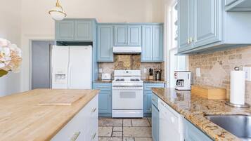 Una cocina con gabinetes azul claro, un refrigerador blanco, una estufa y una encimera de granito.