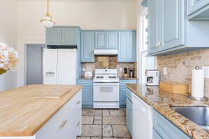 Une cuisine avec des meubles de couleur bleu clair, un réfrigérateur blanc, une cuisinière et un plan de travail en granit.