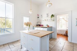 A bright kitchen with a central island, white cabinetry, and a view to the outside. - Renovated Historic House minutes from SF! (Oakland)