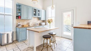 Een moderne keuken met lichtblauwe kastjes, een centraal keukenblok met krukken, een roestvrijstalen koelkast en een witte magnetron.