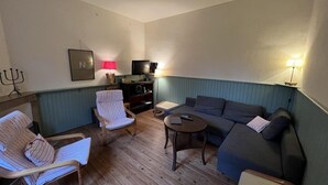 Una sala de estar acogedora con un sofá, sillones, una mesita de centro y un televisor.