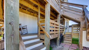 A wooden staircase leading to a covered porch area with a bench and a chair. - Historic suite with a private hot tub! (Avon)