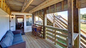 A covered porch with wooden railings, a seating area with a sofa and chairs, and a view of a parking area. - Historic suite with a private hot tub! (Avon)