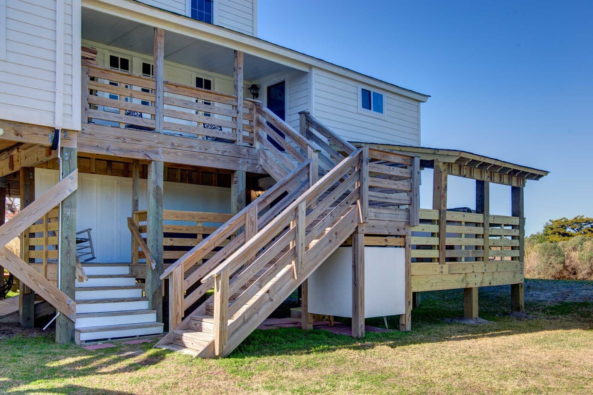 Ein zweistöckiges Holzhaus mit einer Veranda und einer Treppe, die zu der oberen Etage führt.