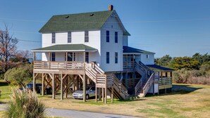 A two-story white house with a green roof, a wooden deck, and a staircase leading to a second level. - Historic suite with a private hot tub! (Avon)