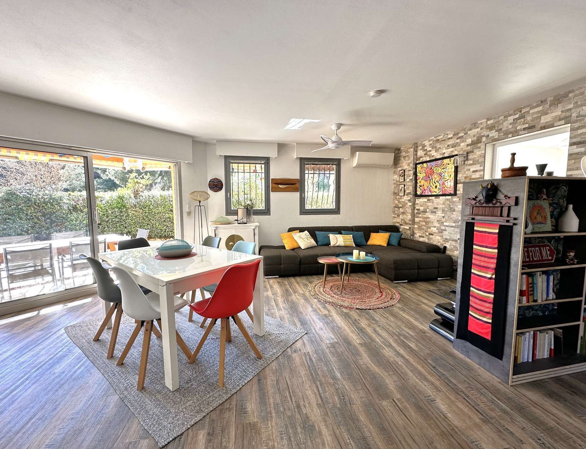 Een moderne woonkamer met een eethoek, een zithoek, een boekenkast en uitzicht op de omgeving.