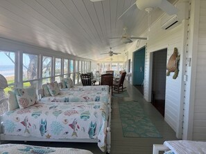 Une chambre de style côtier avec deux lits, un coin repas et une vue sur la mer.