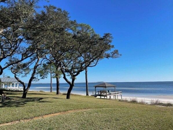 Relax on the beach with a serene ocean view, a gazebo, and a well-manicured lawn.