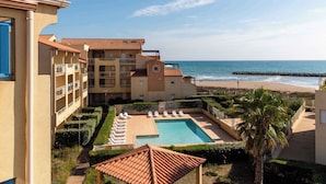 Un hôtel doté d’une piscine, offrant une vue sur la plage et comprenant plusieurs balcons.