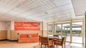 Un espace d’accueil doté d’une grande fenêtre, d’un canapé et d’une table avec des chaises.