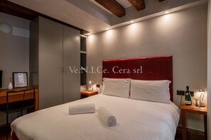 A modern hotel room with a large bed, a wooden desk, and a red headboard.