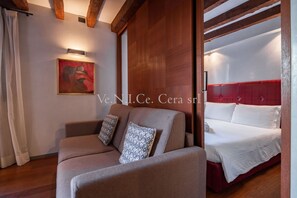 A room with a sofa, a bed with a red headboard, and a painting on the wall. - Ve.N.I.Ce. Cera Canal view (Venezia)