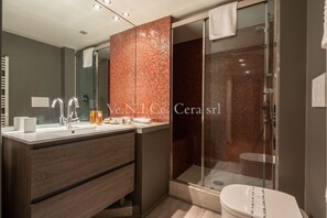 A modern bathroom with a glass shower enclosure, a vanity with a mirror, and a toilet.