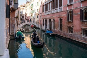 A narrow canal in Venice with gondolas, a bridge, and historic buildings.