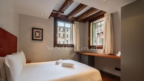 A hotel room with a large bed, wooden beams on the ceiling, a window with curtains, and a framed picture on the wall. - Ve.N.I.Ce. Cera San Moisè (Venezia)