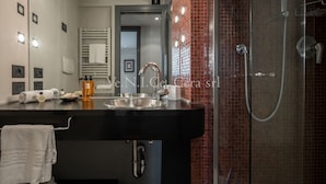 A modern bathroom with a black sink, a glass shower enclosure, and a red-tiled wall. - Ve.N.I.Ce. Cera San Moisè (Venezia)