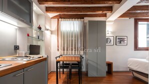 A compact kitchen with a wooden countertop, a dining table with chairs, a grey cabinet, and a built-in TV. - Ve.N.I.Ce. Cera San Moisè (Venezia)