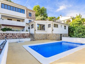 Ein zweistöckiges Haus mit Pool, Steinmauern und Garten.