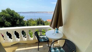 A balcony with two chairs and a table, overlooking a body of water with boats and greenery. - Holiday apartment with two bedrooms and sea views (Jadranovo)