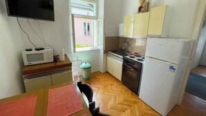 A compact kitchen with a microwave, stove, and refrigerator. There is a window providing natural light and a small trash bin. - Holiday apartment with two bedrooms and sea views (Jadranovo)