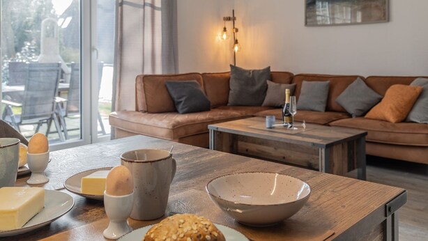 Un salon avec un canapé, une table basse et une table à manger où sont disposés des aliments.