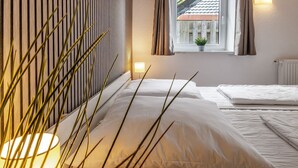 Un lit bien fait, avec du linge de lit blanc, une lampe de chevet et une fenêtre avec des rideaux.