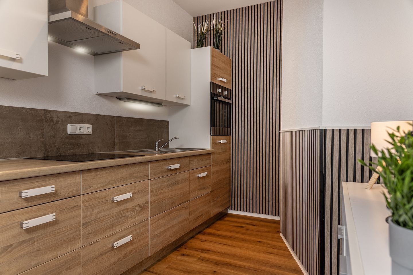 Una cocina moderna con armarios de madera, un lavamanos de acero inoxidable y un horno empotrado.
