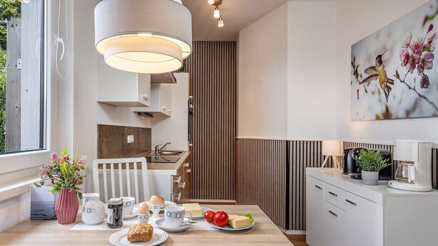 Une cuisine moderne avec un îlot central en bois, des meubles blancs et un luminaire suspendu.