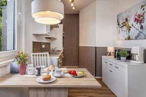 Et moderne køkken med en træø, lyse skabe og en hængende lampe.