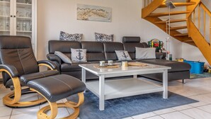 A living room with a sofa, two armchairs, a coffee table, and a staircase. - Vacation home 50059 - Arrive in Altfunnixsiel and feel at home: Quiet (Wittmund)