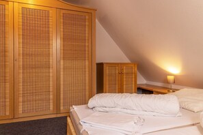 Quarto com cama, guarda-roupa e mesa de cabeceira com abajur.