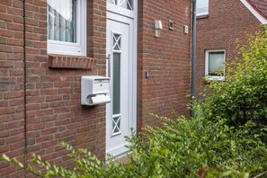 A brick house with a white door, a mailbox, and a small window. - Vacation home 50007 - pure comfort and relaxation: the semi-detached house with (Wittmund)