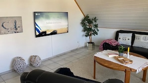 Un salon comprenant un téléviseur, un canapé, une petite table et des objets de décoration.