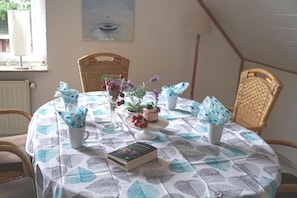 Una mesa de comedor con mantel estampado de hojas, un pastel y varios objetos decorativos.