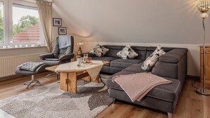 Una sala de estar moderna con sofá, sillón, mesa de centro y lámpara.