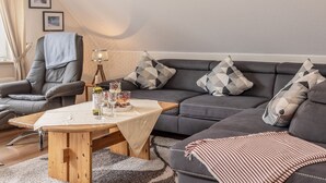 Una sala de estar moderna con un sofá gris, una mesa de centro de madera y una manta con rayas.