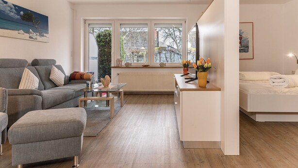 Una sala de estar moderna con un sofá, una mesa de centro y un pequeño comedor.