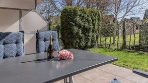 An outdoor patio with a table, cushions, a bottle of wine, and a glass. - Open and flooded with light: the first floor apartment with its 62 square meters was brightly (Wittmund)