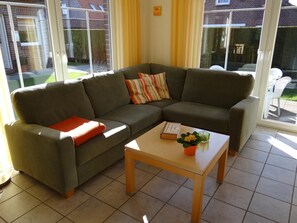A living room with a sectional sofa, a coffee table, and a window with curtains.