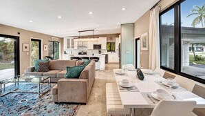 A modern living room with a sofa, coffee table, and dining area. - Private Waterfront Home in Wilton Manors - Dock & BBQ - Minutes From The Beach (Wilton Manors)