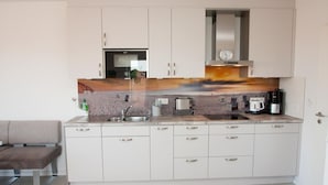 A modern kitchen with white cabinets, a built-in oven, a coffee maker, and a toaster. - Bright and open: The homely apartment, which was completed in 2017 (Wittmund)