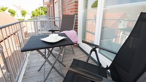 A balcony with a table, a chair, and a sun lounger. - Bright and open: The homely apartment, which was completed in 2017 (Wittmund)